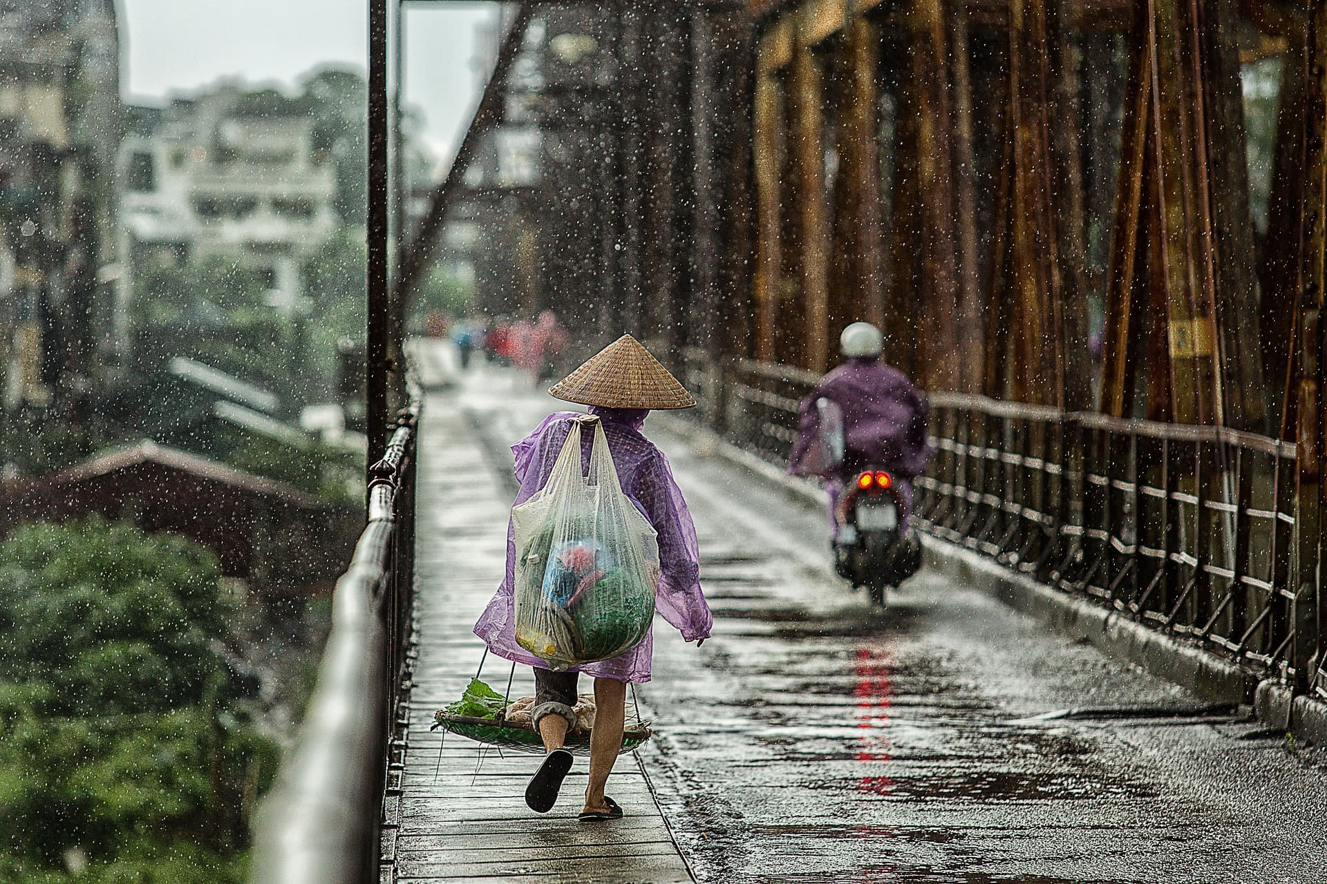 Une personne traversant un pont sous la pluie.