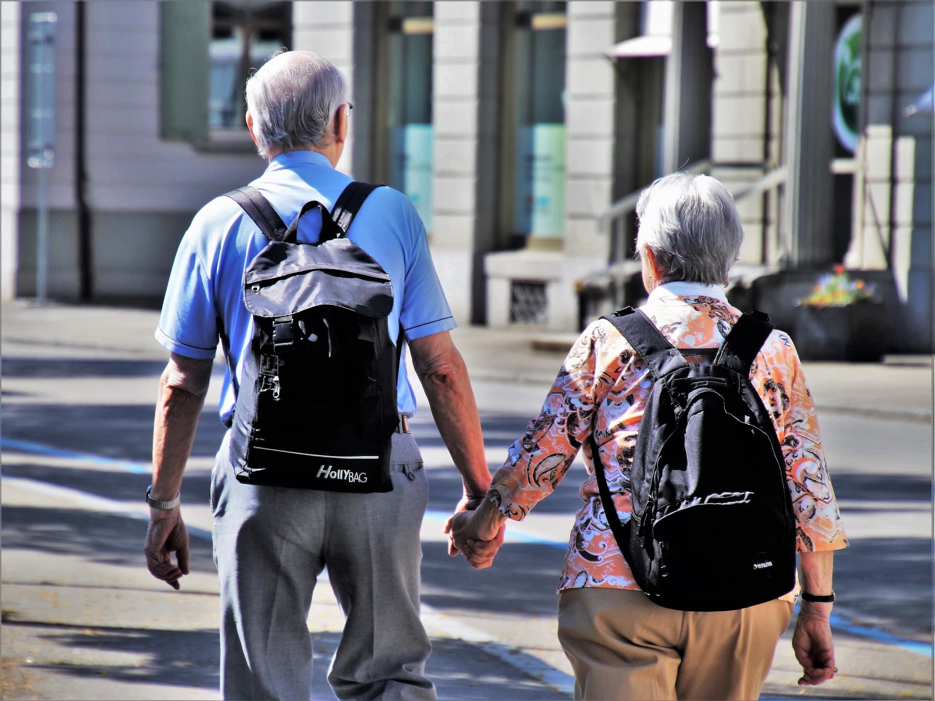 Un couple de personnes âgées marchant main dans la main.