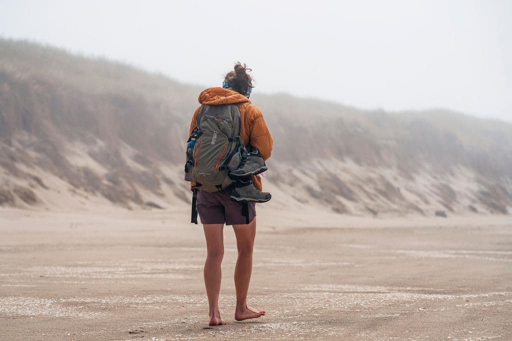 Une femme marche pieds nus sur la plage.