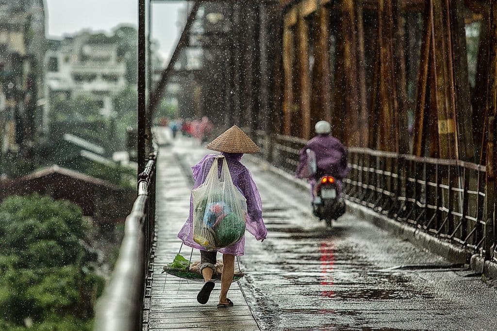 Une personne traversant un pont sous la pluie.